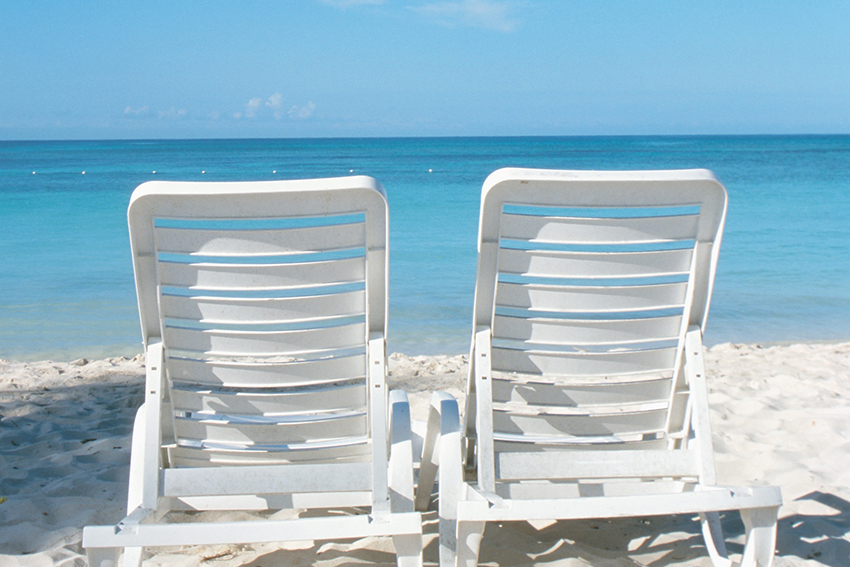 empty beach chairs facing the ocean